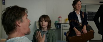 Movie still from “Juliet, Naked” (2018), directed by Jesse Peretz – A young boy sitting in front of a doctor; Medium shot, Over the shoulder angle