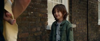 Movie still from “Juliet, Naked” (2018), directed by Jesse Peretz – A little boy standing next to a brick wall; Close Up shot, Over the shoulder angle