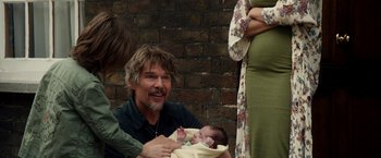 Movie still from “Juliet, Naked” (2018), directed by Jesse Peretz – An older man holding a baby in his arms; Medium shot, Over the shoulder angle