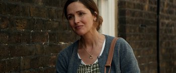 Movie still from “Juliet, Naked” (2018), directed by Jesse Peretz – A person wearing a necklace near a brick wall; Close Up shot, Over the shoulder angle