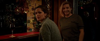 Movie still from “Juliet, Naked” (2018), directed by Jesse Peretz – Two women standing next to each other in front of a wall; Medium shot, Over the shoulder angle