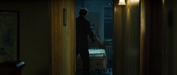 Movie still from “Jumper” (2008), directed by Doug Liman – A man standing in front of a bed in a dark room; Wide shot, Over the shoulder angle