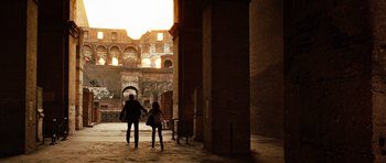 Movie still from “Jumper” (2008), directed by Doug Liman – A woman and a child are walking through a courtyard; Wide shot, Over the shoulder angle