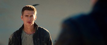 Movie still from “Jumper” (2008), directed by Doug Liman – A man in a black jacket is standing in front of a camera; Close Up shot, Over the shoulder angle