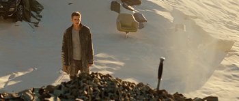 Movie still from “Jumper” (2008), directed by Doug Liman – A man standing in the sand next to a pile of rocks; Wide shot, High angle