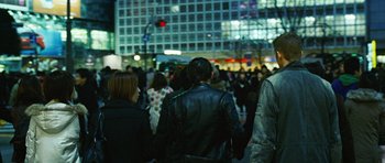 Movie still from “Jumper” (2008), directed by Doug Liman – A group of people walking down a street at night; Medium shot, Over the shoulder angle
