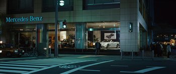 Movie still from “Jumper” (2008), directed by Doug Liman – A man walking across the street in front of a car dealership; Wide shot, High angle