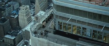 Movie still from “Jumper” (2008), directed by Doug Liman – A group of people standing on the side of a building next to stairs; Extreme Wide shot, High angle