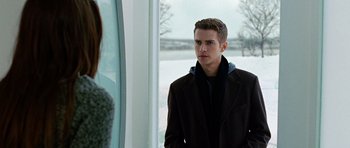 Movie still from “Jumper” (2008), directed by Doug Liman – A man in a black coat standing in front of a window; Medium shot, Over the shoulder angle