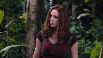 Movie still from “Jumanji: Welcome to the Jungle” (2017), directed by Jake Kasdan – A woman with long red hair wearing a red shirt; Medium shot, Low angle