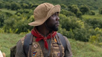 Movie still from “Jumanji: Welcome to the Jungle” (2017), directed by Jake Kasdan – A man wearing a hat and vest in the woods; Close Up shot, Low angle