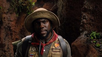 Movie still from “Jumanji: Welcome to the Jungle” (2017), directed by Jake Kasdan – A man wearing a hat and a vest in the woods; Close Up shot, Over the shoulder angle