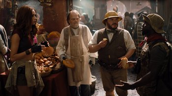Movie still from “Jumanji: Welcome to the Jungle” (2017), directed by Jake Kasdan – Two men are standing in front of a table of food; Medium shot, Over the shoulder angle