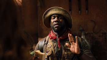 Movie still from “Jumanji: Welcome to the Jungle” (2017), directed by Jake Kasdan – A man wearing a hat and holding a piece of paper; Close Up shot, Over the shoulder angle