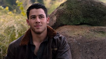 Movie still from “Jumanji: Welcome to the Jungle” (2017), directed by Jake Kasdan – A man in a brown jacket sitting on top of a rock; Close Up shot, Over the shoulder angle