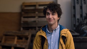 Movie still from “Jumanji: Welcome to the Jungle” (2017), directed by Jake Kasdan – A young man with curly hair wearing a yellow jacket; Close Up shot, Over the shoulder angle