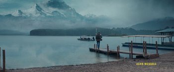 Movie still from “Jungle” (2017), directed by Greg McLean – A person standing on a dock near a body of water; Extreme Wide shot, Low angle
