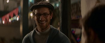 Movie still from “Jungle” (2017), directed by Greg McLean – A man wearing glasses and a hat smiling for the camera; Close Up shot, Over the shoulder angle