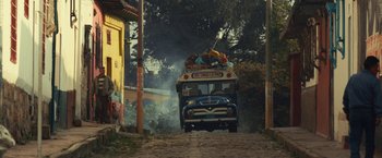 Movie still from “Jungle” (2017), directed by Greg McLean – An old bus is driving down a dirt road; Wide shot, Low angle