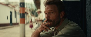 Movie still from “Jungle” (2017), directed by Greg McLean – A person with a beard smoking a cigarette; Close Up shot, Over the shoulder angle