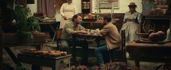Movie still from “Jungle” (2017), directed by Greg McLean – Two people sitting at a table with a cup of coffee; Medium shot, Over the shoulder angle