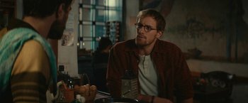 Movie still from “Jungle” (2017), directed by Greg McLean – A man sitting at a table in front of a window; Medium shot, Over the shoulder angle