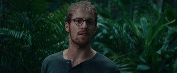 Movie still from “Jungle” (2017), directed by Greg McLean – A person wearing glasses near a tree; Close Up shot, Over the shoulder angle