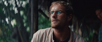 Movie still from “Jungle” (2017), directed by Greg McLean – A person wearing glasses and a striped shirt; Close Up shot, Low angle