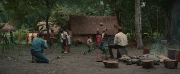 Movie still from “Jungle” (2017), directed by Greg McLean – A group of people standing in a dirt field; Wide shot, Over the shoulder angle