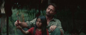 Movie still from “Jungle” (2017), directed by Greg McLean – A man sitting next to a little girl in the woods; Close Up shot, Over the shoulder angle