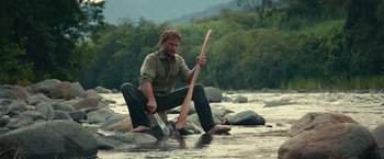 Movie still from “Jungle” (2017), directed by Greg McLean – A man in the water holding a wooden stick; Medium shot, Low angle
