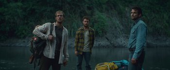 Movie still from “Jungle” (2017), directed by Greg McLean – Two men standing next to a body of water; Wide shot, High angle