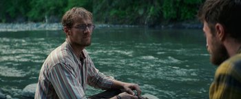 Movie still from “Jungle” (2017), directed by Greg McLean – A man sitting in a boat on a body of water; Close Up shot, Over the shoulder angle