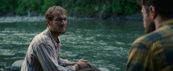 Movie still from “Jungle” (2017), directed by Greg McLean – A man sitting on the side of a body of water; Close Up shot, Over the shoulder angle