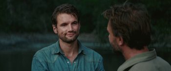 Movie still from “Jungle” (2017), directed by Greg McLean – A man in a blue shirt talking to another man in a blue shirt; Close Up shot, Over the shoulder angle
