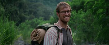 Movie still from “Jungle” (2017), directed by Greg McLean – A man with a backpack and a roll of paper on his back; Close Up shot, Over the shoulder angle