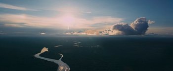 Movie still from “Jungle” (2017), directed by Greg McLean – The sun is setting over a large body of water; Extreme Wide shot, High angle