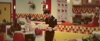 Movie still from “Jungle” (2017), directed by Greg McLean – A man holding a tray of hot dogs in front of him; Medium shot, High angle
