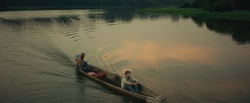 Movie still from “Jungle” (2017), directed by Greg McLean – Two people in a boat on a river; Extreme Wide shot, High angle