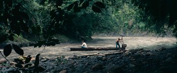 Movie still from “Jungle” (2017), directed by Greg McLean – Two people in a canoe on a river; Extreme Wide shot, High angle