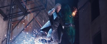 Movie still from “Jupiter Ascending” (2015), directed by Lilly Wachowski – A man holding a gun while standing next to another man holding fireworks; Wide shot, Overhead angle
