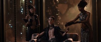 Movie still from “Jupiter Ascending” (2015), directed by Lilly Wachowski – A man sitting on top of a couch next to a woman; Medium shot, Over the shoulder angle