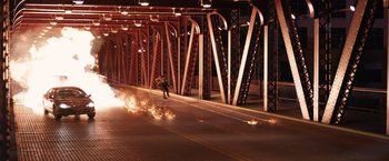 Movie still from “Jupiter Ascending” (2015), directed by Lilly Wachowski – A man standing on the side of a road near a fire; Extreme Wide shot, High angle