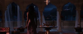 Movie still from “Jupiter Ascending” (2015), directed by Lilly Wachowski – A woman standing in front of a table in a room; Wide shot, Over the shoulder angle