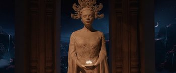 Movie still from “Jupiter Ascending” (2015), directed by Lilly Wachowski – A statue of a woman holding a lit candle in her hands; Medium shot, Low angle