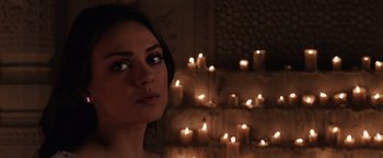 Movie still from “Jupiter Ascending” (2015), directed by Lilly Wachowski – A beautiful young woman standing in front of a wall of lit candles; Close Up shot, Over the shoulder angle