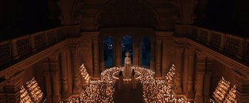 Movie still from “Jupiter Ascending” (2015), directed by Lilly Wachowski – A group of people standing in a room with candles; Extreme Wide shot, High angle