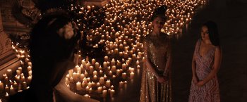 Movie still from “Jupiter Ascending” (2015), directed by Lilly Wachowski – A woman standing in front of a room filled with lit candles; Extreme Wide shot, High angle