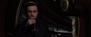 Movie still from “Jupiter Ascending” (2015), directed by Lilly Wachowski – A man holding a wine glass in his hand; Close Up shot, Low angle