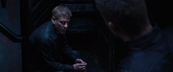Movie still from “Jupiter Ascending” (2015), directed by Lilly Wachowski – A man sitting on the ground talking to another man; Medium shot, Over the shoulder angle